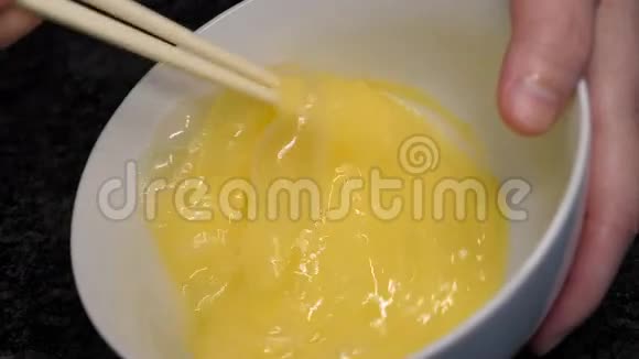 女人在碗里用筷子搅拌鸡蛋的慢动作视频的预览图