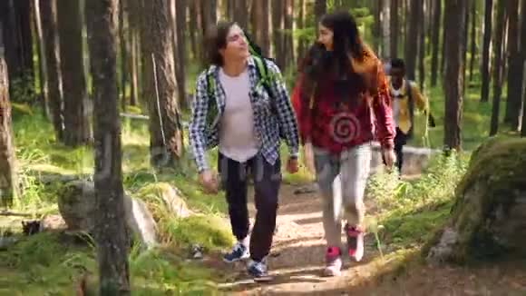 冒险的朋友带着背包在野生森林里徒步旅行穿着舒适的休闲服装交谈大自然视频的预览图