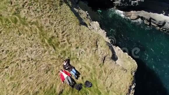 两个女人躺在爱尔兰西海岸悬崖边上的空中无人机镜头视频的预览图