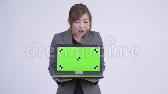 年轻快乐的亚洲女商人带着笔记本电脑看上去很惊讶视频的预览图