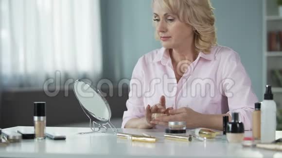 高级女性使用昂贵的化妆来隐藏年龄相关的皮肤变化视频的预览图