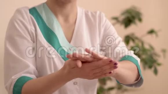 按摩治疗师穿着白色外套在按摩前小心用油擦手视频的预览图