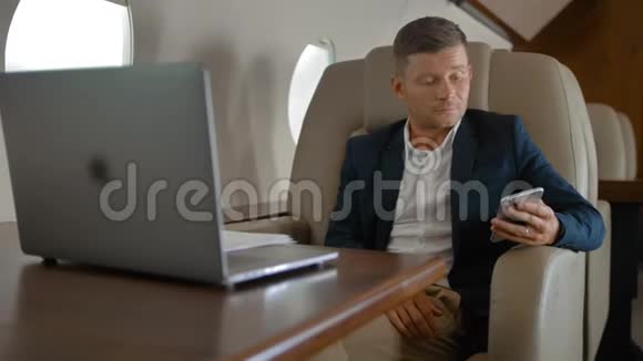 商务人士坐在舒适的扶手椅上坐在私人飞机舱里聊天视频的预览图