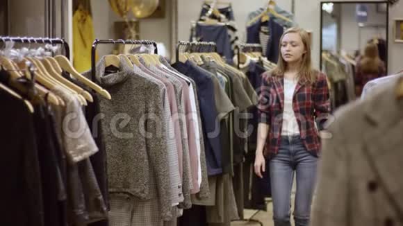 年轻漂亮的女人在服装店里找衣服带着一个人走近一看却把衣服收起来视频的预览图