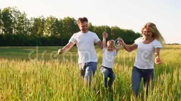 幸福的家庭父亲母亲和儿子穿着白色t恤在田野里奔跑视频的预览图