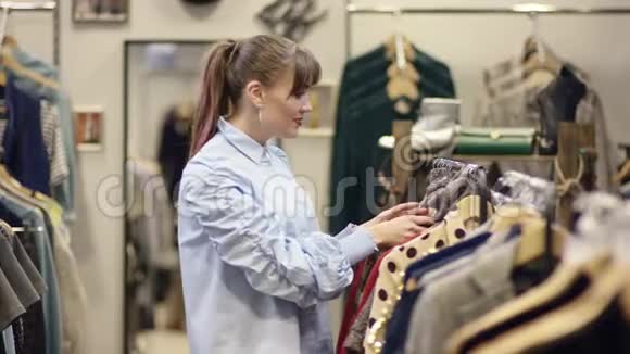 成年美女在服装店里找衣服看着漂亮的套头衫却又把它带回了别的地方视频的预览图