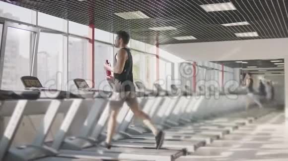跑步的人在健身房的跑步机上喝水视频的预览图