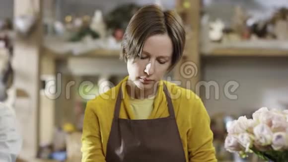 穿着黄色衬衫的女人在花店工作用铅笔在笔记本上做笔记相机也随之变化视频的预览图