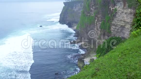 美丽的悬崖上的海洋海岸和水波上的天际线景观高山峭壁覆盖着热带植物视频的预览图