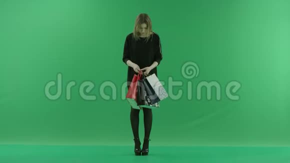 年轻女子看着她的购物袋里彩色钥匙绿色背景视频的预览图