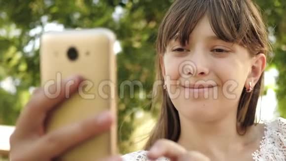 年轻女孩在平板电脑上和朋友聊天美丽的女孩在智能手机上写了一封春天夏天在公园的信视频的预览图