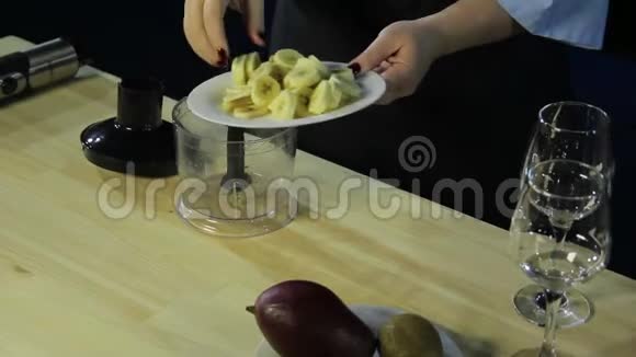 一个女人把一片香蕉放进搅拌杯里视频的预览图