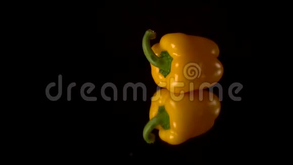 新鲜的黄椒铺在黑镜桌上黑色背景视频的预览图