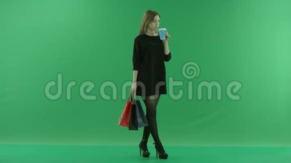 漂亮的年轻女人手里拿着袋子喝咖啡颜色关键绿色背景视频的预览图