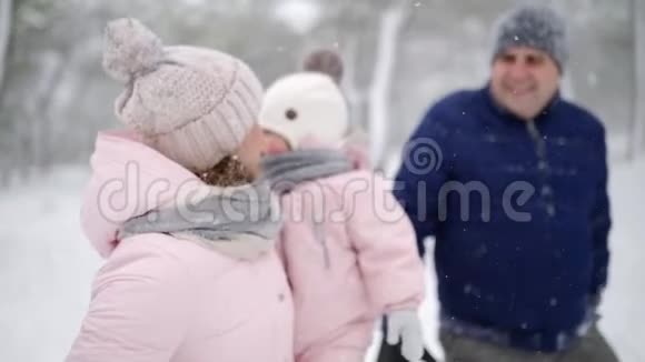 友好的全家人在降雪的情况下在冬天的森林里散步父亲母亲和女儿视频的预览图