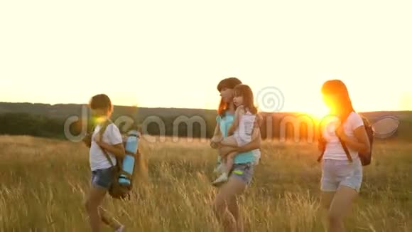 快乐的女孩在夕阳下穿越田野徒步旅行者女孩一家人在草地上散步女孩带着背包旅行视频的预览图
