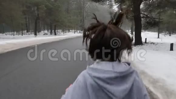 年轻迷人的白种人女孩在冬天带着耳机在雪地公园跑步关闭后跟射击慢动作视频的预览图