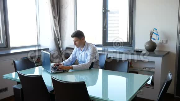 穿着蓝色衬衫的人在家里用笔记本电脑工作一个漂亮的金发女人跟他调情抚摸他的头视频的预览图