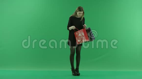 年轻漂亮的女士正在检查她的购物袋彩色钥匙绿色背景视频的预览图
