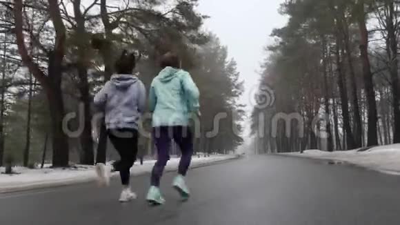 快乐的年长和年轻的高加索女人在冬天的雪地公园里奔跑交谈和微笑后面跟着视频的预览图