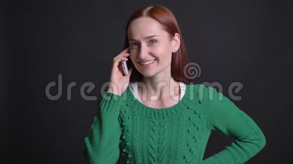 有着红发的有魅力的白种人女性的特写肖像在电话上交谈微笑着视频的预览图