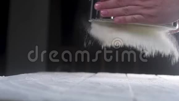 蛋糕敲着一个金属筛子筛小麦白面粉面粉落在桌子上的灰尘上制作烘焙比萨饼面团视频的预览图