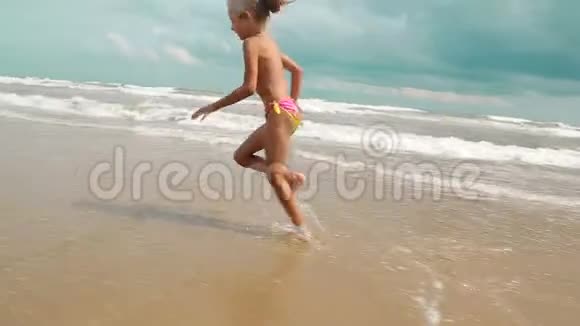 两个迷人的小女孩沿着海岸沿着大海奔跑节日快乐的孩子们视频的预览图