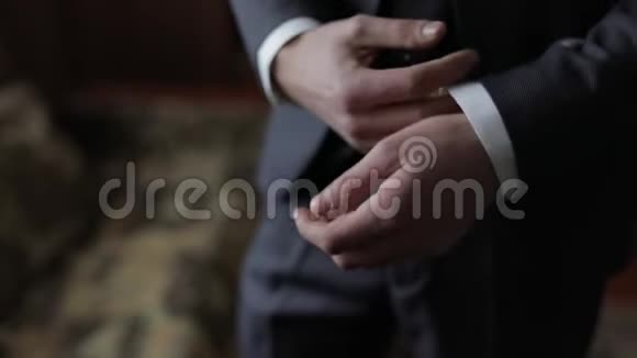 英俊的新郎把袖口固定在夹克上结婚的早晨商人视频的预览图