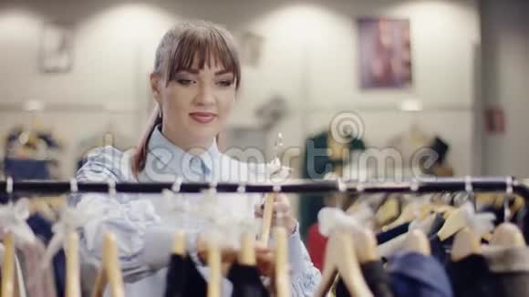 一位迷人的年轻女售货员把一件连衣裙放在服装店的衣架上然后走开了视频的预览图