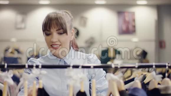 漂亮的年轻女人从服装店里的一排衣服里拿出一条裙子然后就走了视频的预览图