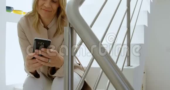 妇女在家中的楼梯上使用手机视频的预览图