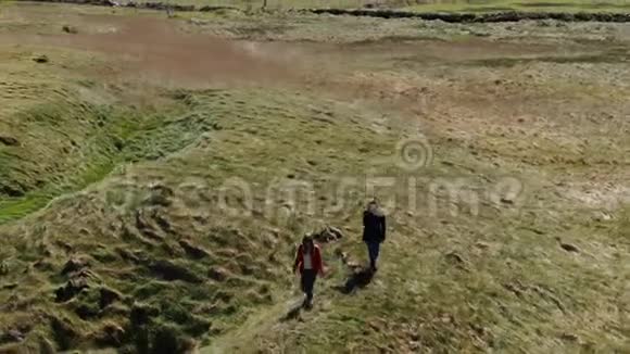 爱尔兰的两个女孩在阳光明媚的日子里走在基尔基的悬崖上空中无人机俯瞰视频的预览图