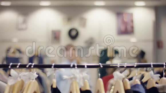 漂亮的年轻快乐的女人走到服装店里的衣服架边找新衣服检查一些衣服视频的预览图
