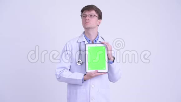 快乐的年轻医生一边思考一边展示数码平板电脑视频的预览图