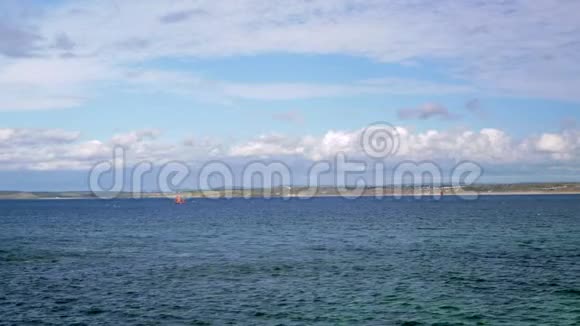 一艘小帆船在海里漂浮远处可见岩石海岸视频的预览图
