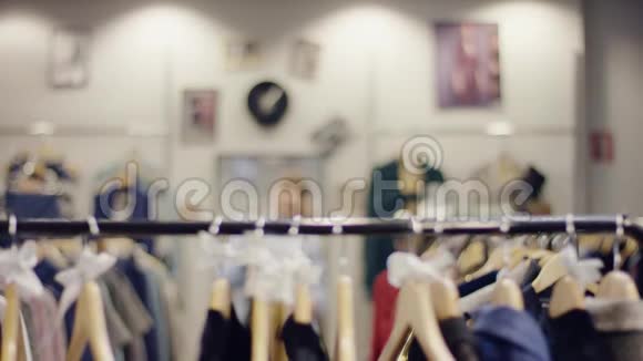 漂亮的年轻女售货员走到一家服装店的衣服架边在那里放了一些裙子视频的预览图