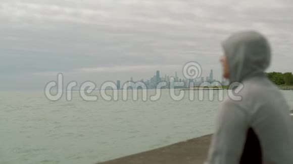 戴着兜帽的运动员眺望城市的景色慢动作视频的预览图