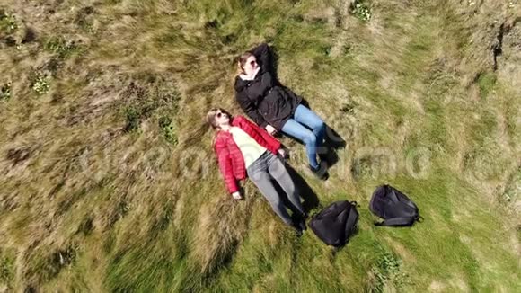 两个女人躺在爱尔兰西海岸悬崖边上的空中无人机镜头视频的预览图