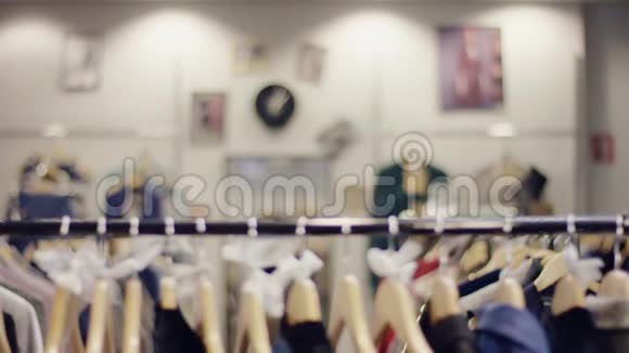 一位漂亮的年轻女士在一家服装店里走过一排衣服然后快速地看了看衣服视频的预览图