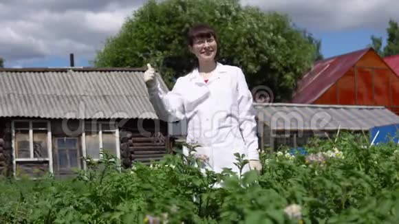 年轻的女科学家在马铃薯田的背景下展示拇指视频的预览图