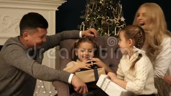 父母和两个孩子在室内圣诞树附近玩得开心视频的预览图