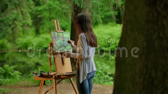 一位年轻的艺术家女性画一幅风景画的后景视频的预览图