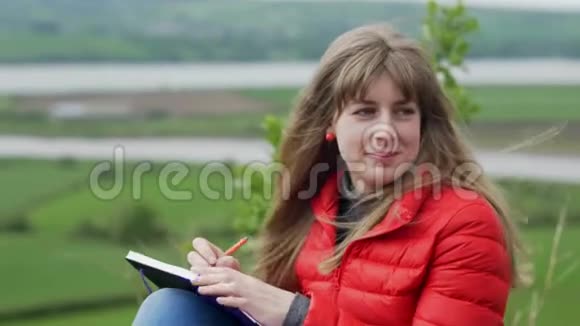 年轻女子坐在爱尔兰的绿色大自然中写笔记视频的预览图