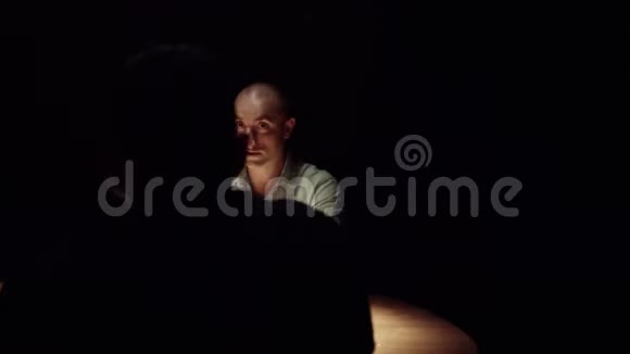 三个英俊的成熟男人围着木桌坐在黑暗的房间里视频的预览图