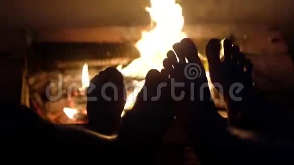 一对相爱的夫妇正坐在火堆附近休息并温暖他们的赤脚视频的预览图