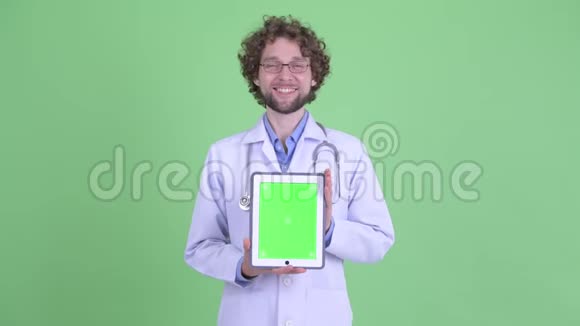 一位满脸胡须的年轻医生正在给他提供数码平板电脑视频的预览图