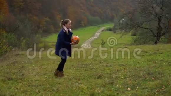 美丽的女孩在秋天的森林里玩球她很快乐微笑着她很有趣秋天里视频的预览图