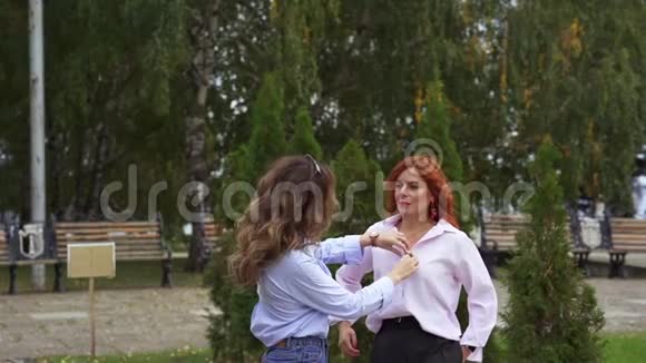 两个栗色红发的美女互相交流一个女人使另一个女人衬衫挺直视频的预览图