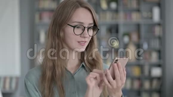 成功的年轻女性在使用智能手机画像视频的预览图