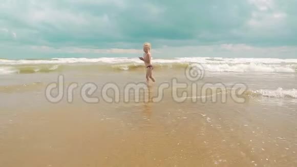 两个迷人的小女孩沿着海岸沿着大海奔跑节日快乐的孩子们视频的预览图